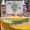 Birthday party dessert table with bright yellow table cloth on a bright sunny day
