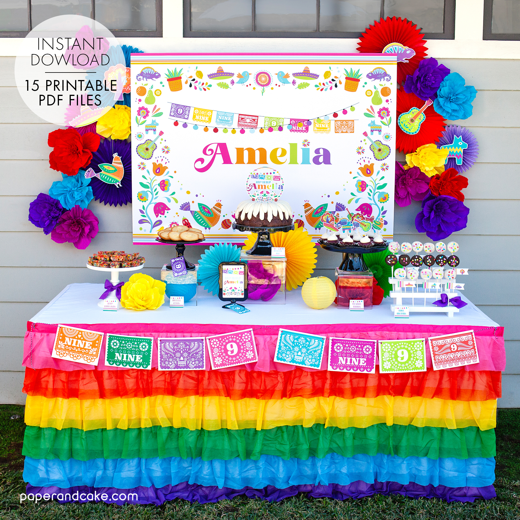 A festive fiesta dessert table is decorated with a colorful ruffled rainbow tablecloth and a matching backdrop poster, creating a celebratory atmosphere.